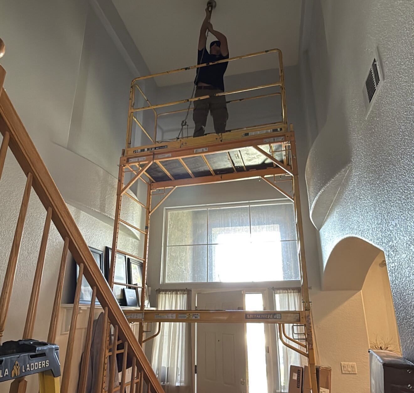 Electrician on scaffolding installing chandelier at high ceiling — Cyber Electric LLC