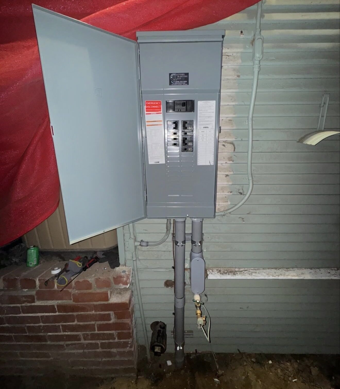 New 200A main panel mid-installation on exterior wall with conduit runs below — Cyber Electric LLC
