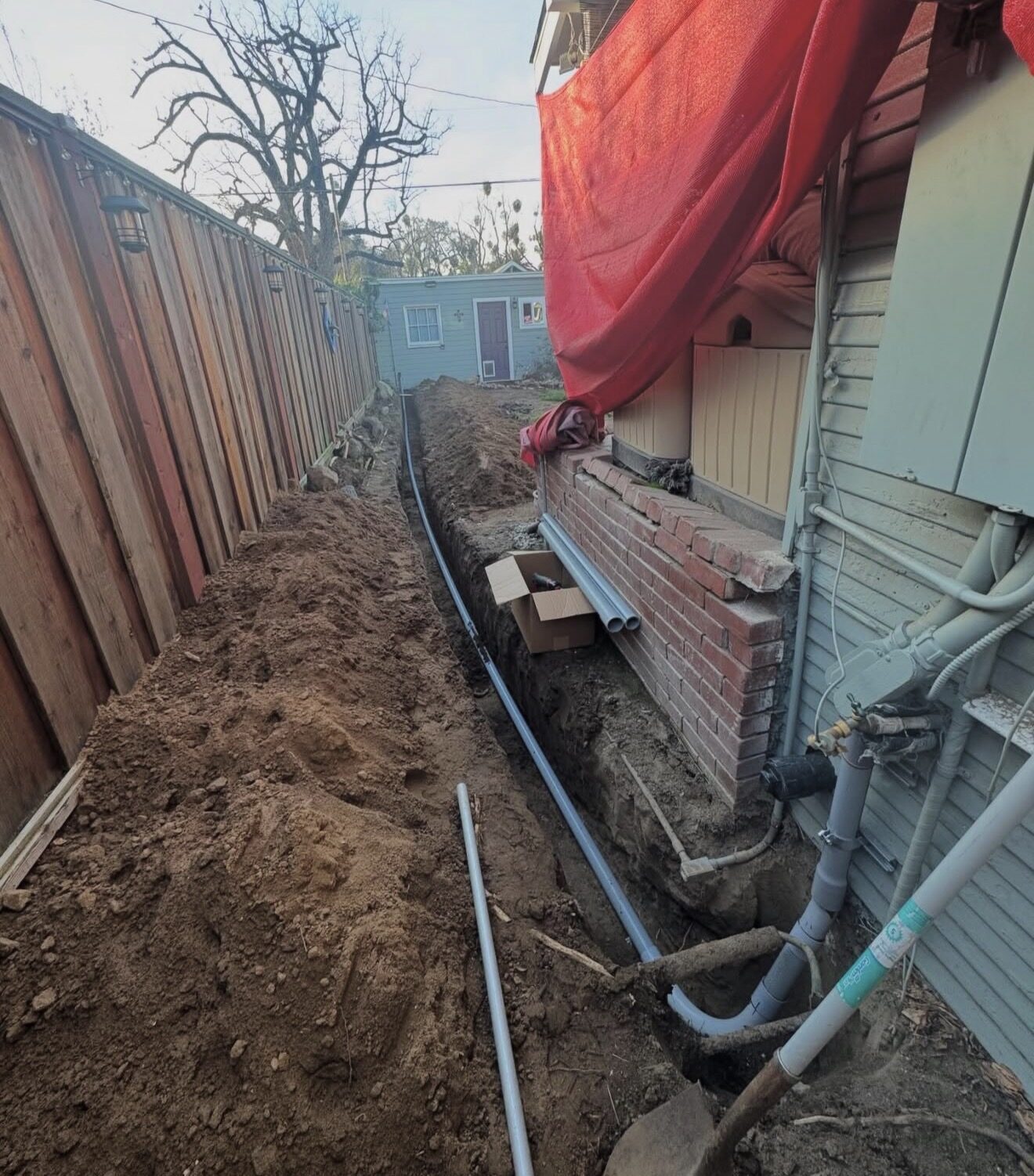 Underground conduit trench running along side of house between fence and foundation — Cyber Electric LLC