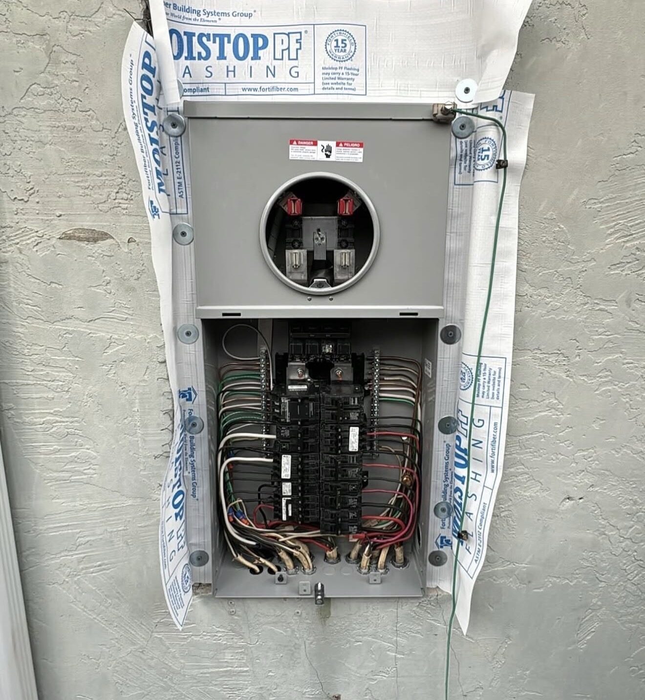 New panel set in rough opening with MoistStop flashing and meter socket visible — Cyber Electric LLC