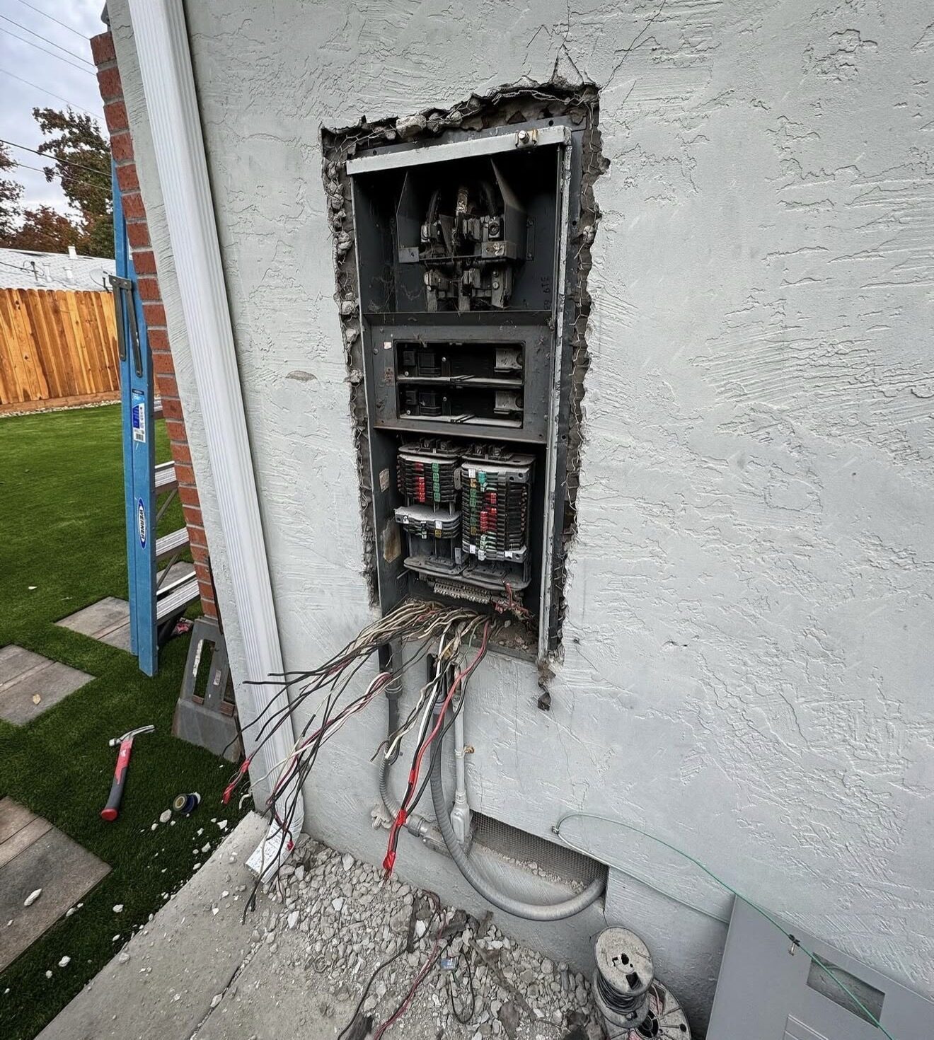 Zinsco panel completely removed, rough opening in stucco wall, branch circuit wires hanging out — Cyber Electric LLC